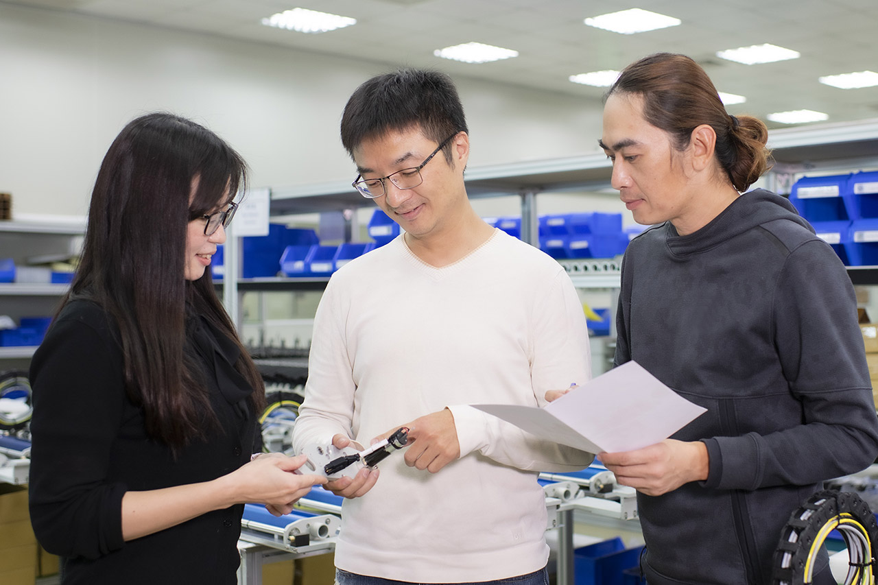 SHL Technologies Senior Engineer Weber Yu and two colleagues inspect a PCB printing machine sub-assembly component.